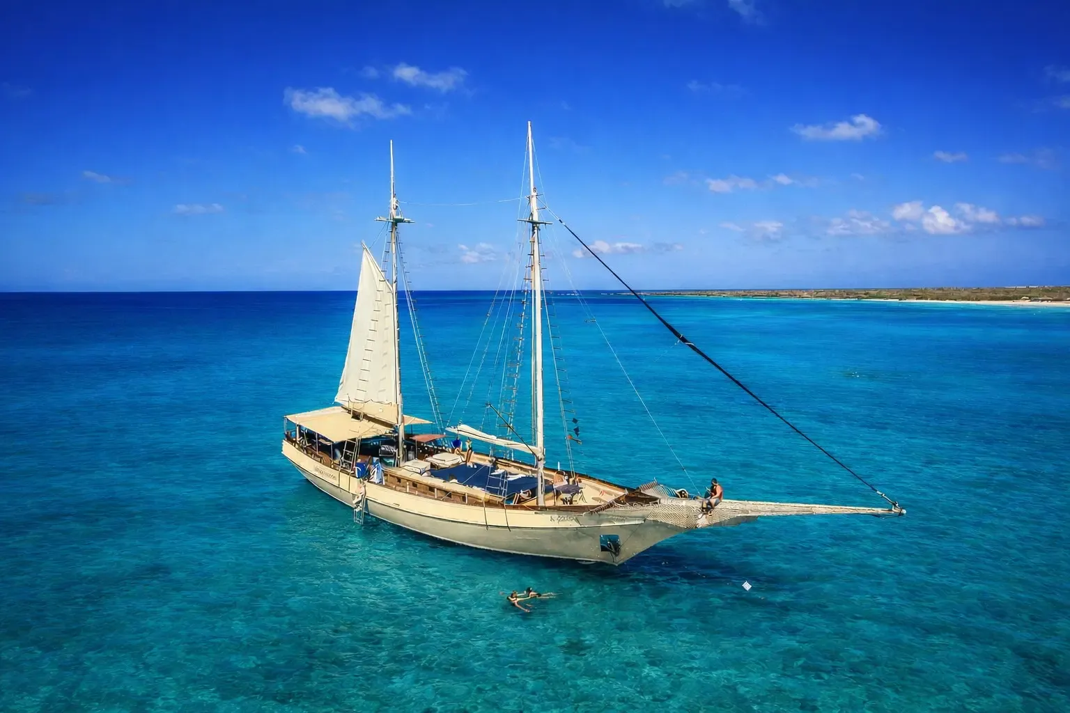 Flagship Aruba's schooner anchored in turquoise water, guests swimming alongside