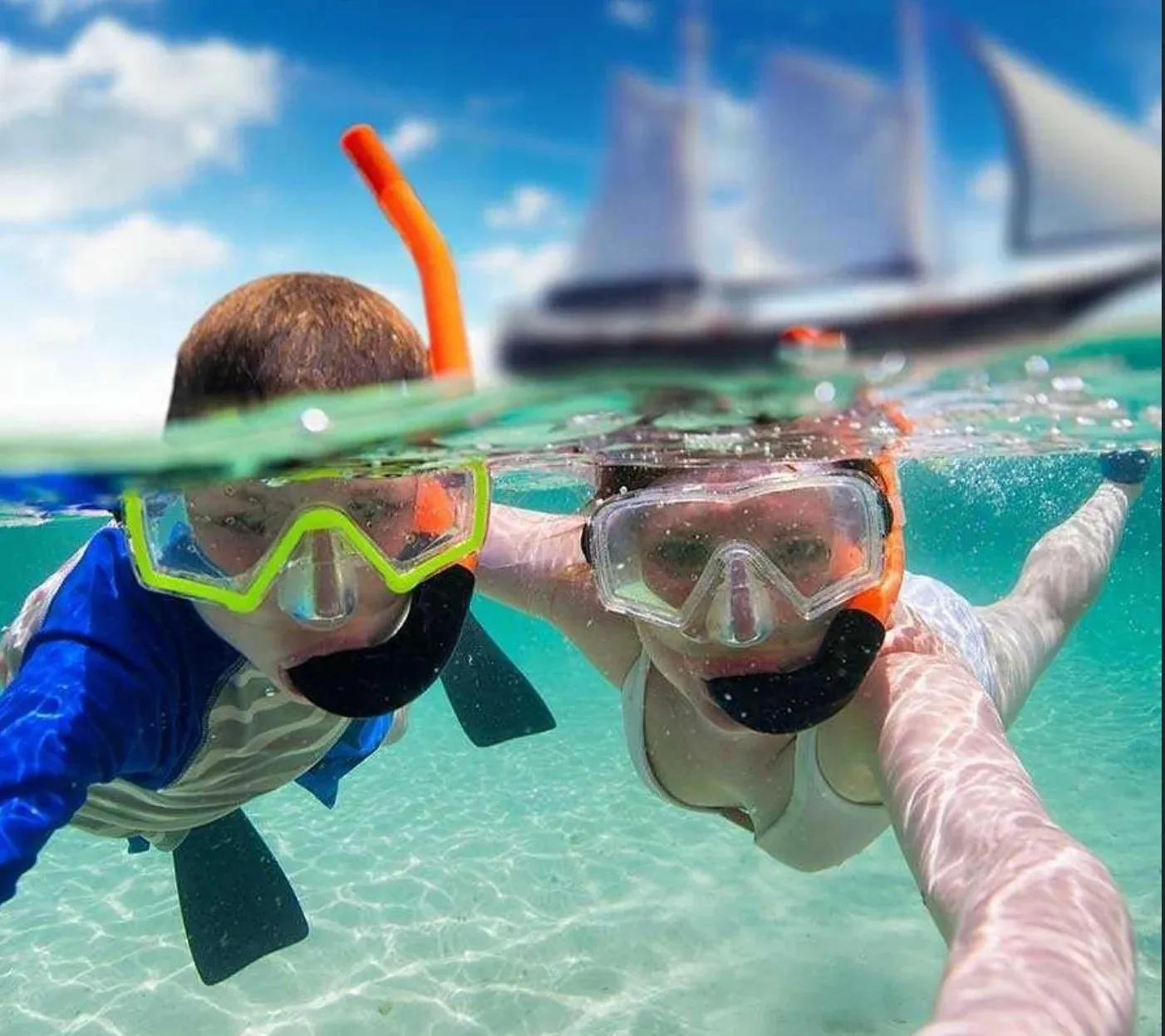 A family snorkeling together with the schooner in the background